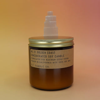 The Golden Coast - 12.5 oz Large Concentrated Soy Wax Candle in front of a selenite tower all on a pink and yellow background.