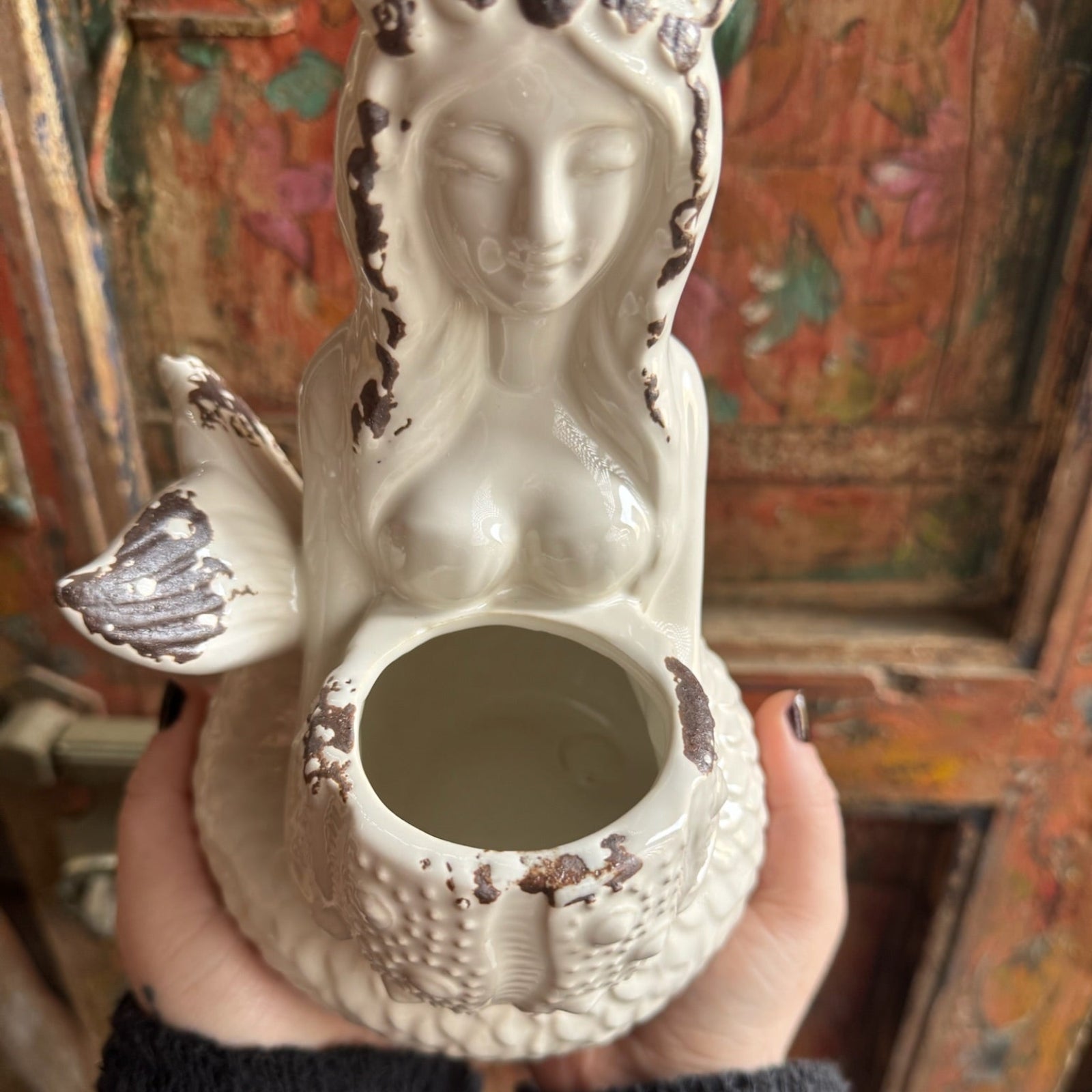 Someone holding the Goddess Mermaid & Urchin Planter in front of a wood background.