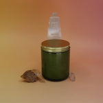 The P.F. Candle Co. - Vanilla & Ghost Pepper Candle in front of a selenite tower on a pink and yellow background.