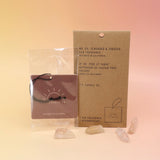 The P.F. Candle Co. Teakwood & Tobacco - Car Fragrance on a pink and yellow background.