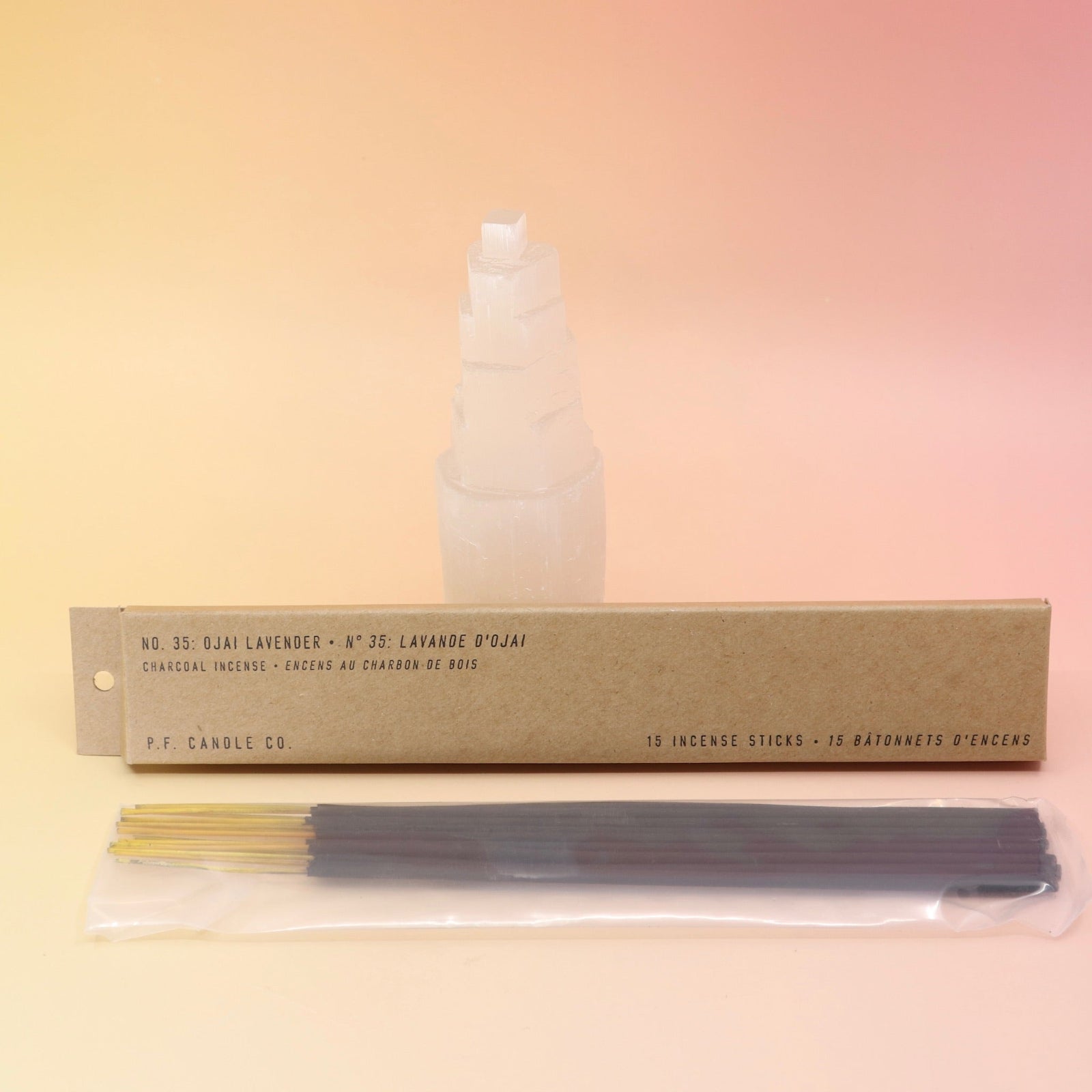The P.F. Candle Co. Ojai Lavender - Incense in front of a selenite tower all on a pink and yellow background.