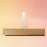 The P.F. Candle Co. Teakwood & Tobacco Incense in front of a selenite tower all on a pink and yellow background.