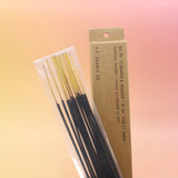 The P.F. Candle Co. Teakwood & Tobacco Incense on a pink and yellow background.