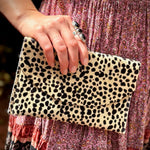 Some holding the Tiny Spotted Hair on Hide Envelope Pouch Clutch next to their dress.