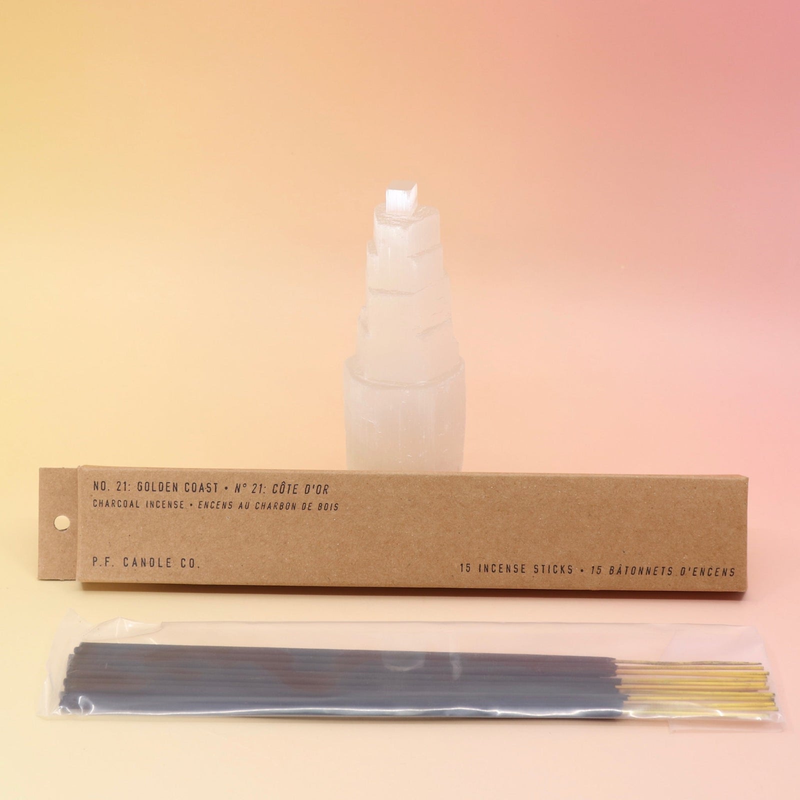 The P.F. Candle Co. Golden Coast Incense in front of a selenite tower on a pink and yellow background.
