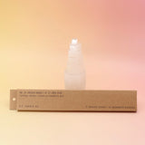 The P.F. Candle Co. Golden Coast Incense in front of a selenite tower on a pink and yellow background.