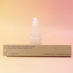 The Amber & Moss Incense - Pack of 15 from P.F. Candle Co. in front of a selenite tower on a pink and yellow background.