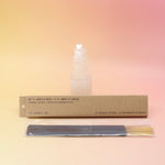 The Amber & Moss Incense - Pack of 15 from P.F. Candle Co. in front of a selenite tower on a pink and yellow background.