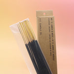 The Amber & Moss Incense - Pack of 15 from P.F. Candle Co. on a pink and yellow background.