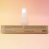 The back of the P.F. Candle Co. incense packaging against a selenite tower on a pink and yellow background.