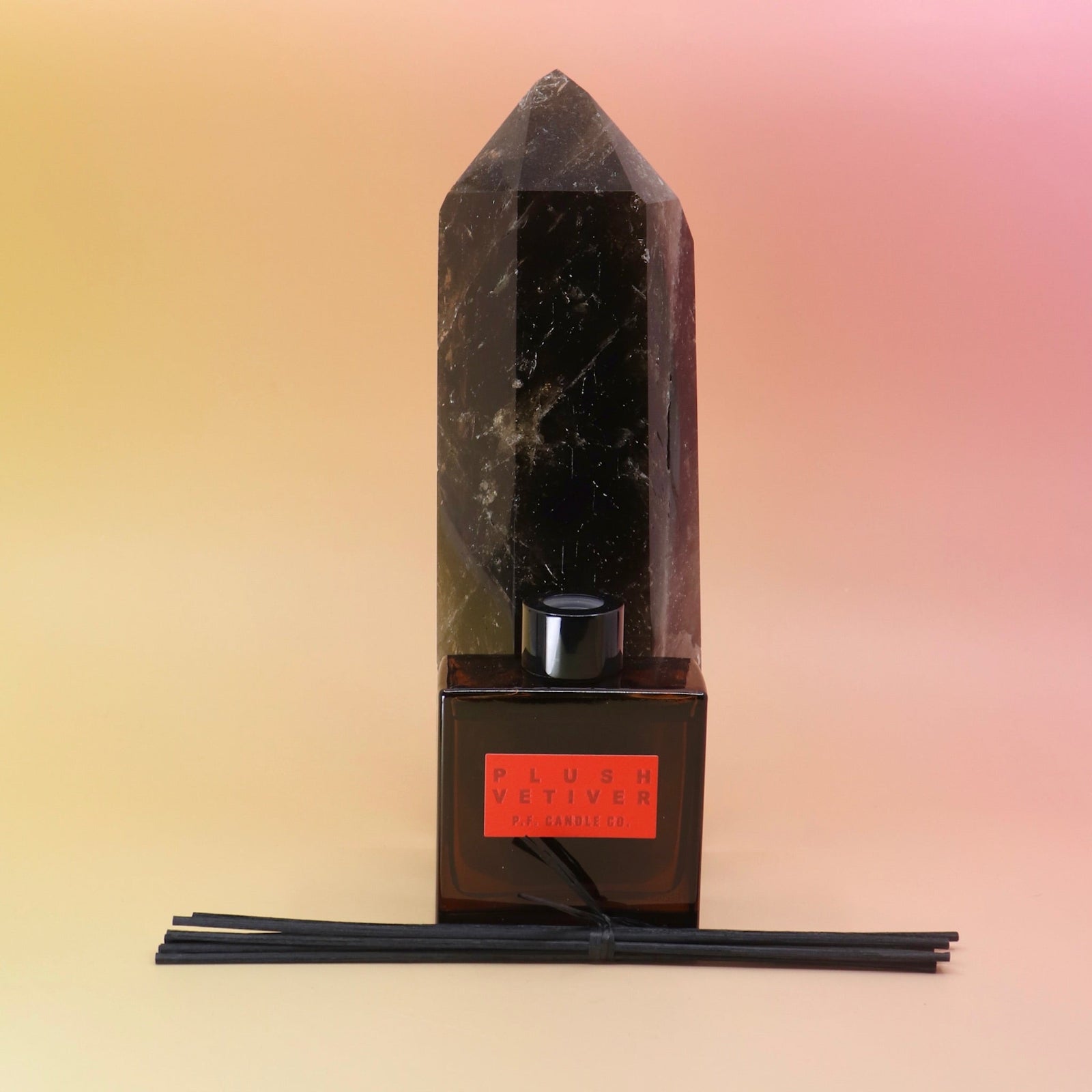 The Plush Vetiver - HI-FI Reed Diffuser in front of a crystal tower on a pink and yellow background.