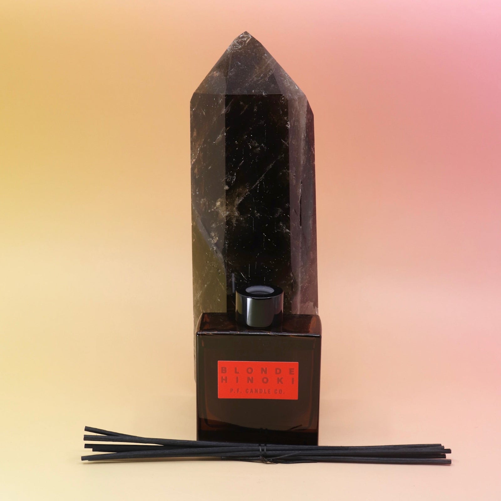 The Blonde Hinoki – HI-FI Reed Diffuser bottle in front of a crystal tower on a pink and yellow background.