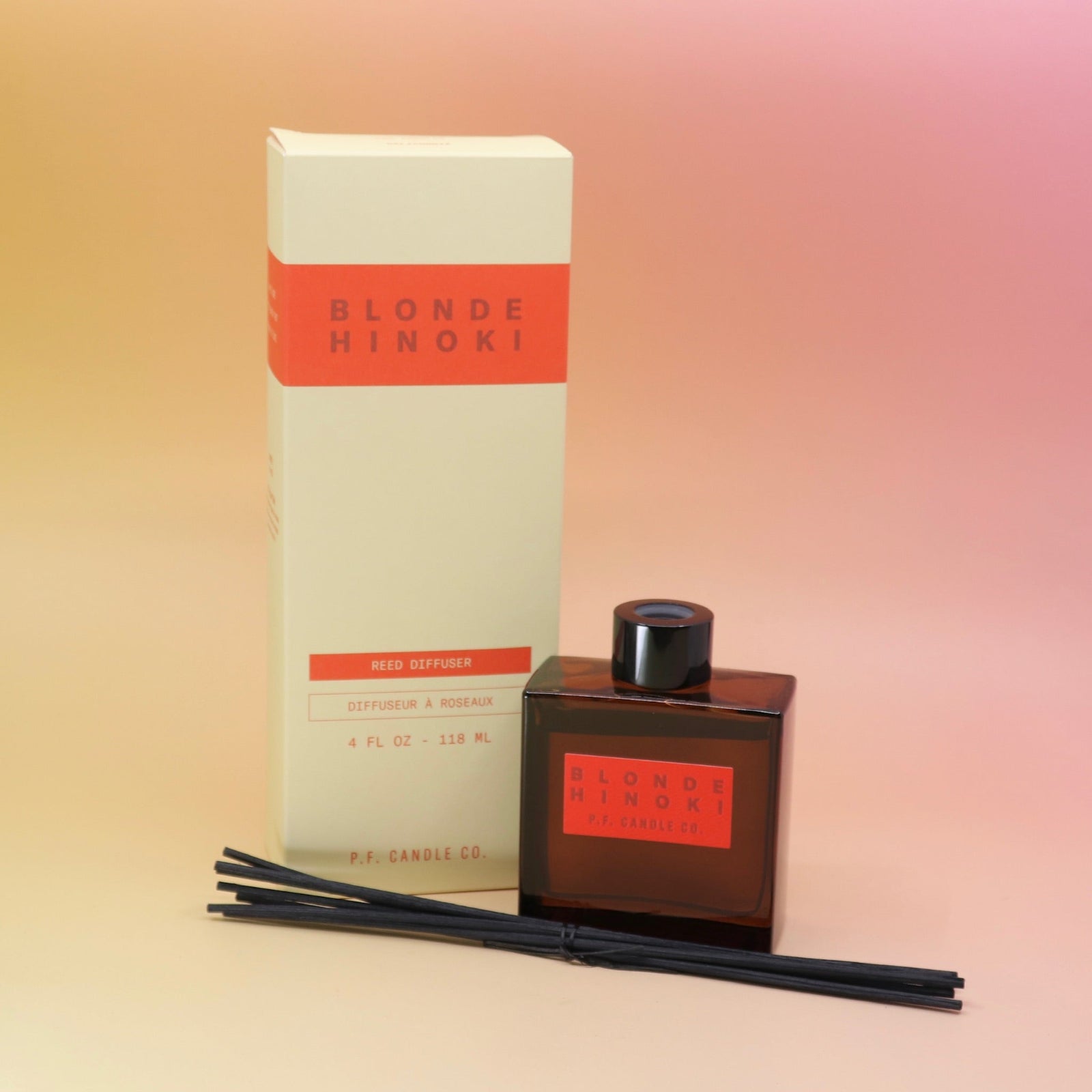 The Blonde Hinoki – HI-FI Reed Diffuser next to its packaging with its reed diffusers in front all on a pink and yellow background.