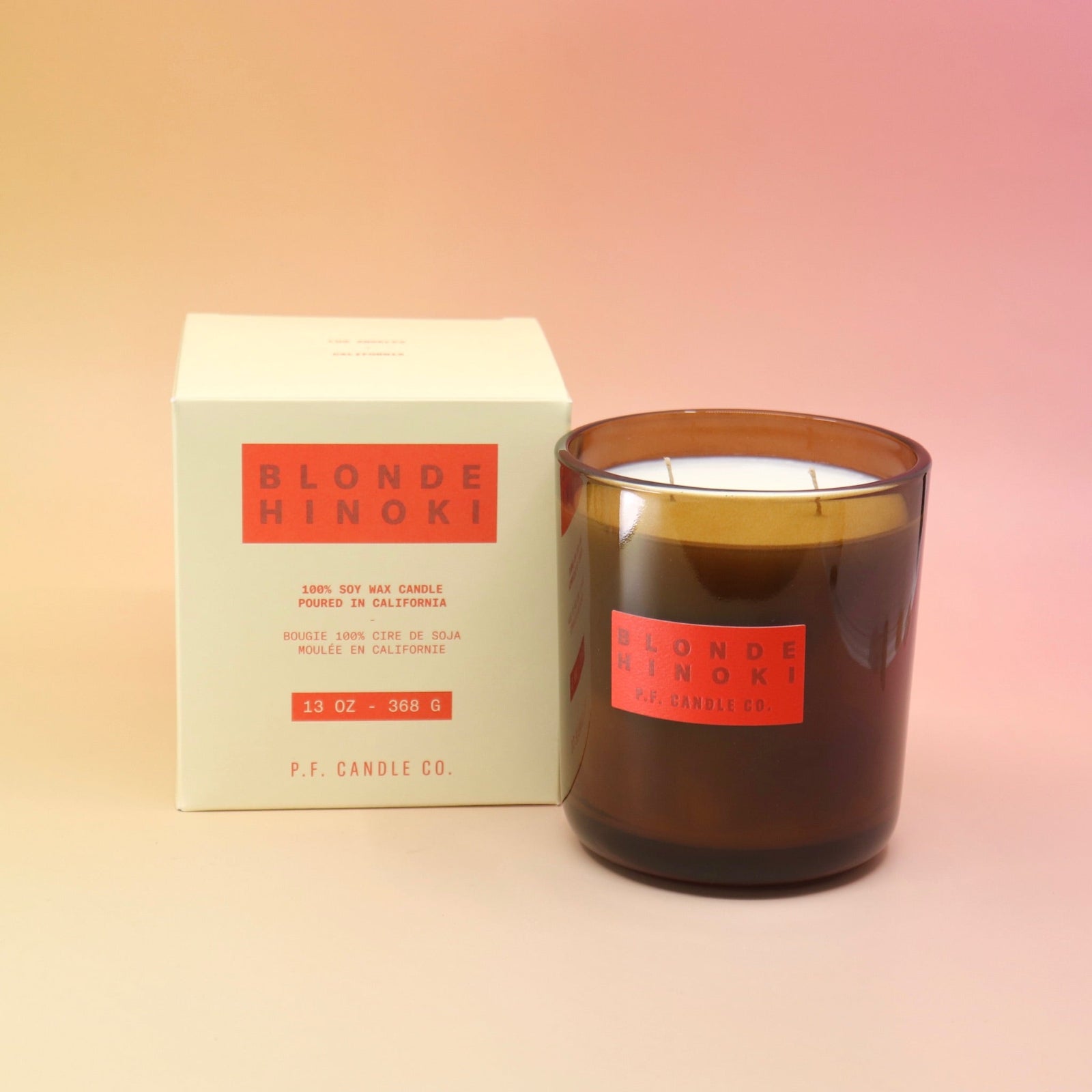 The Blonde Hinoki - HI-FI Soy Wax Candle next to its packaging all on a pink and yellow background.