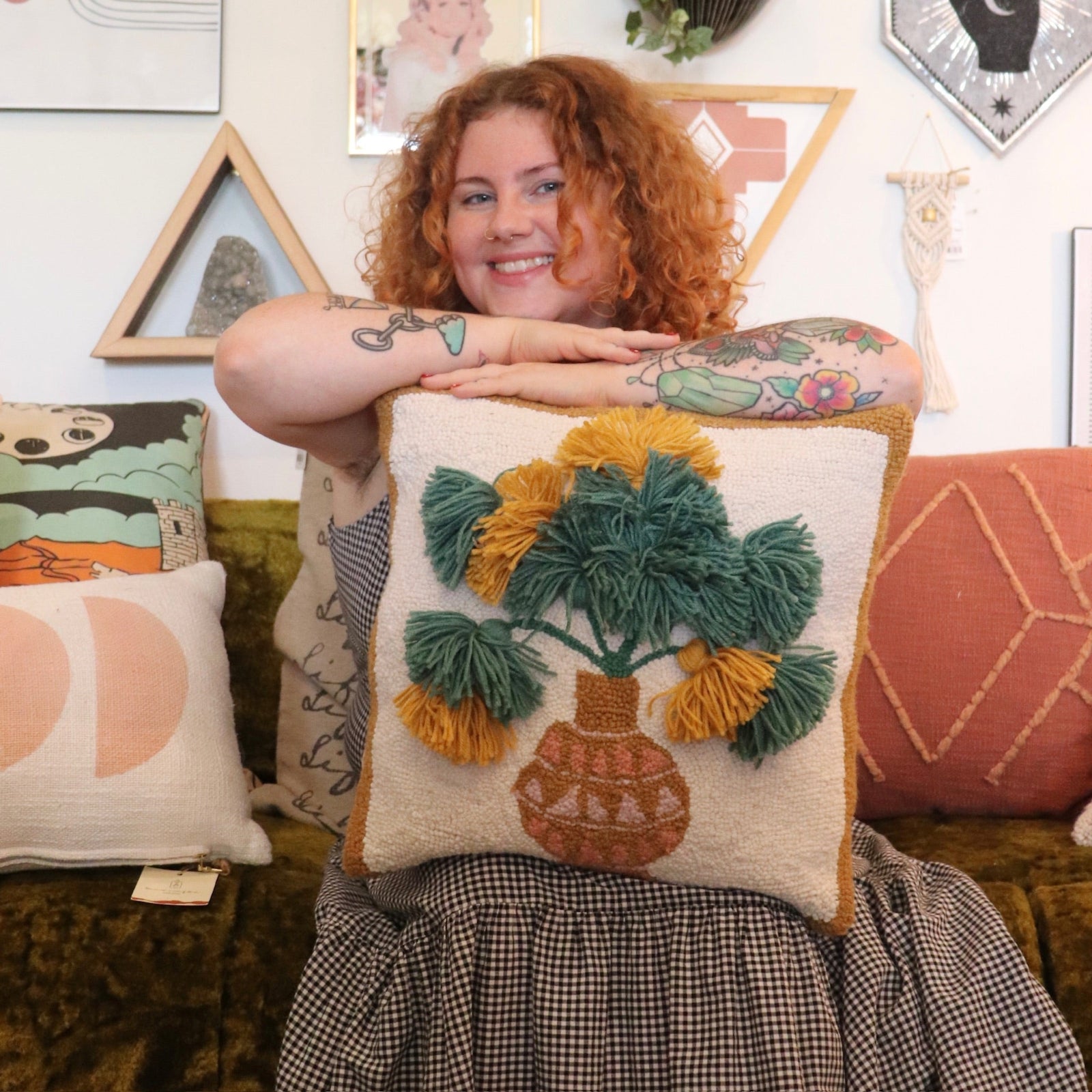 A woman holding the Papyrus Wool Hook Pillow.