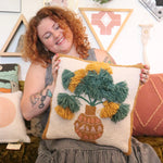 A woman holding the Papyrus Wool Hook Pillow.