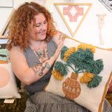 A woman holding the Papyrus Wool Hook Pillow.
