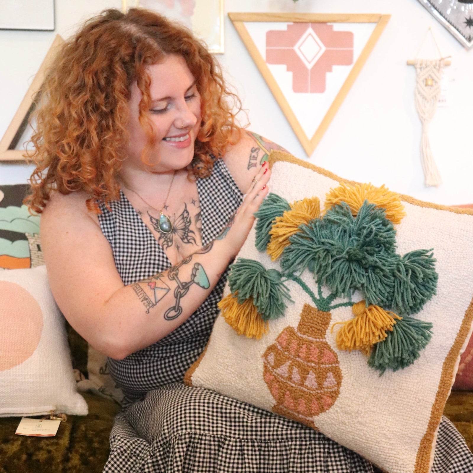 A woman holding the Papyrus Wool Hook Pillow.