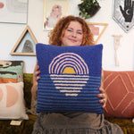 A woman holding the Blue Sunset Hook Pillow.
