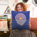 A woman holding the Blue Sunset Hook Pillow.