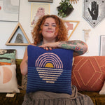 A woman holding the Blue Sunset Hook Pillow.