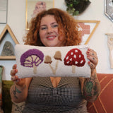 A woman holding the Mushrooms Wool Hook Pillow.