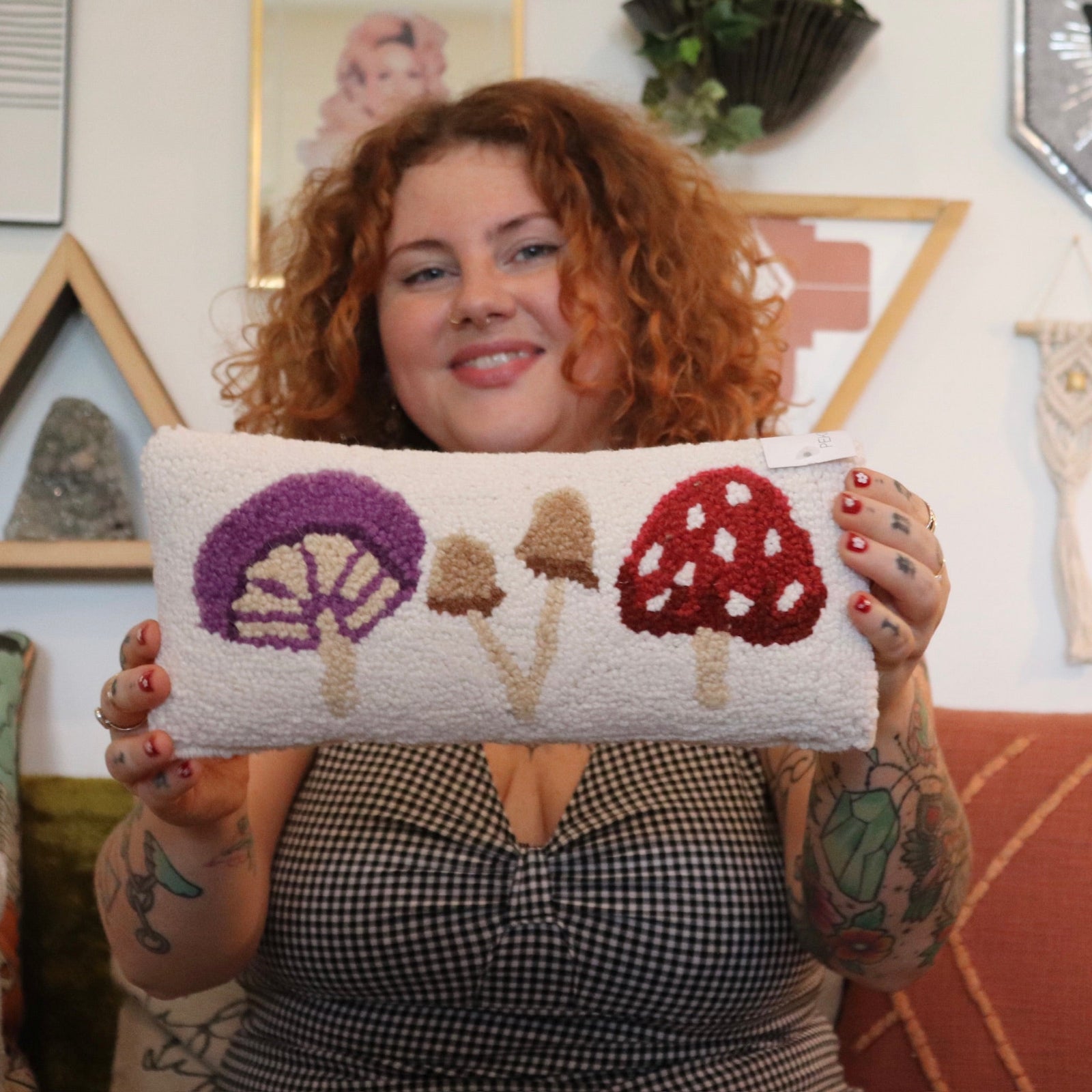 A woman holding the Mushrooms Wool Hook Pillow.