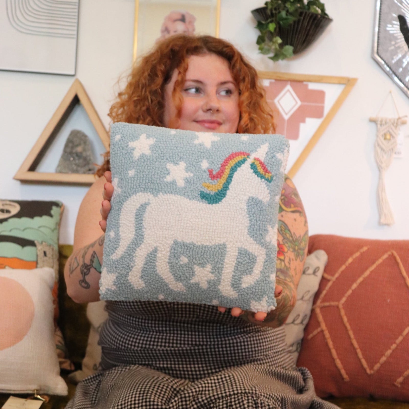 A woman holding the Unicorn Magic Wool Hook Pillow.