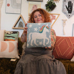 A woman holding the Unicorn Magic Wool Hook Pillow.