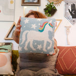 A woman holding the Unicorn Magic Wool Hook Pillow.