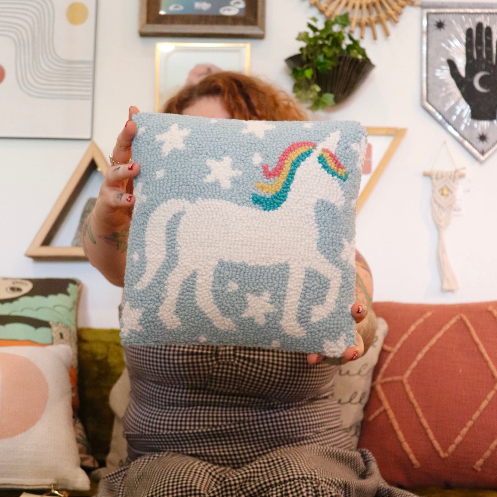 A woman holding the Unicorn Magic Wool Hook Pillow.