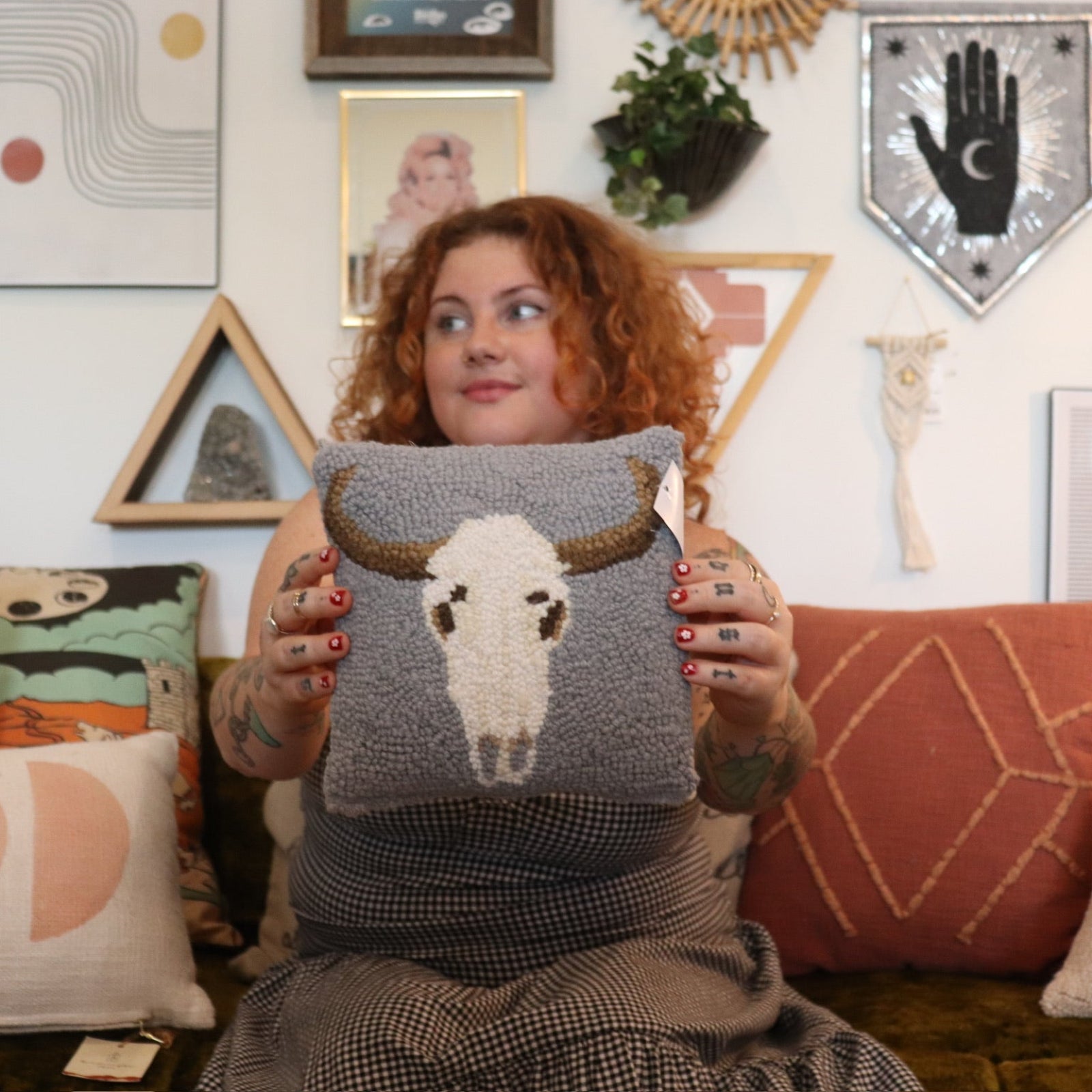 A woman holding the Cow Skull Wool Hook Pillow.