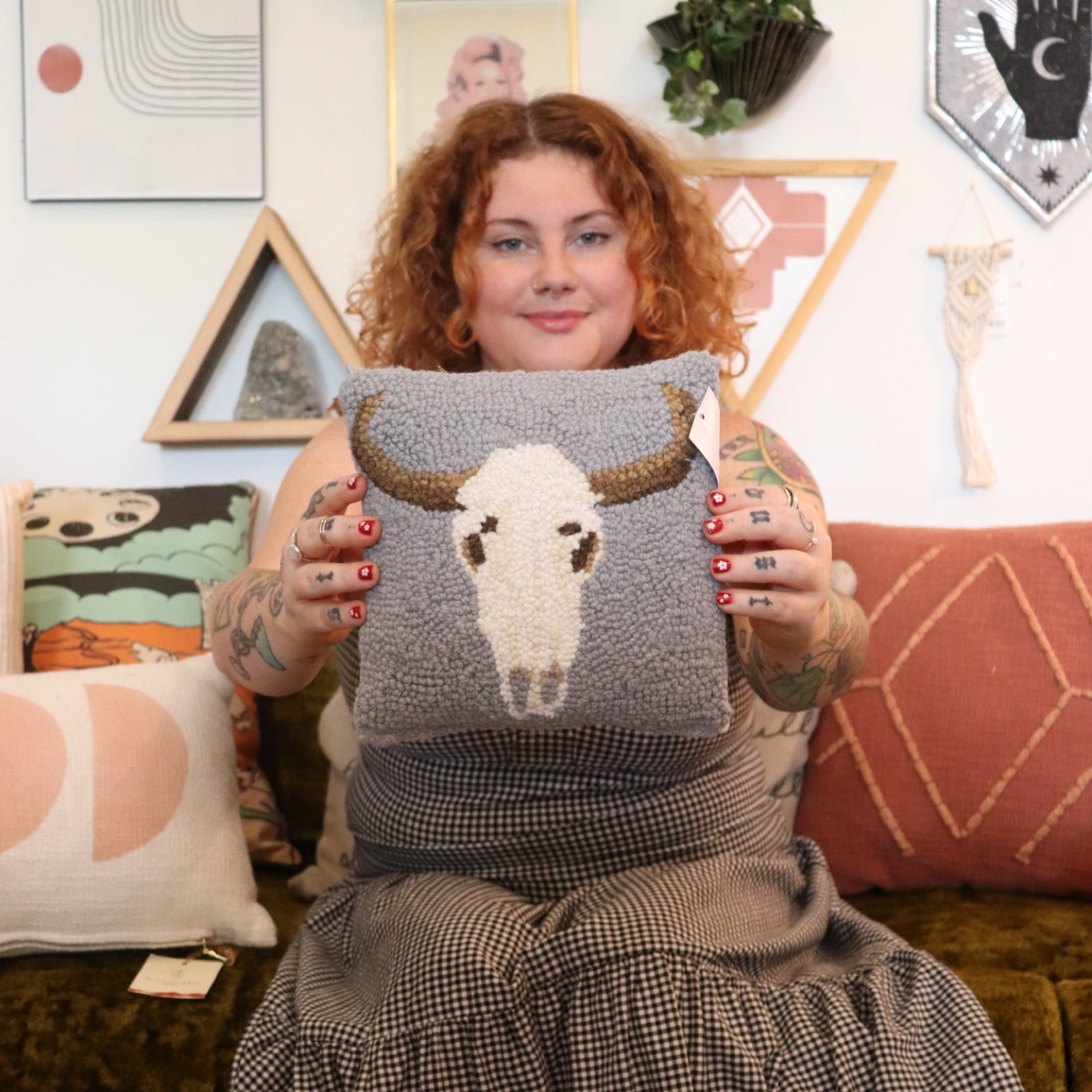 A woman holding the Cow Skull Wool Hook Pillow.
