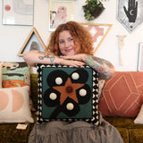 A woman holding theDiamonds & Pearls with Pom Poms Wool Hook Pillow.