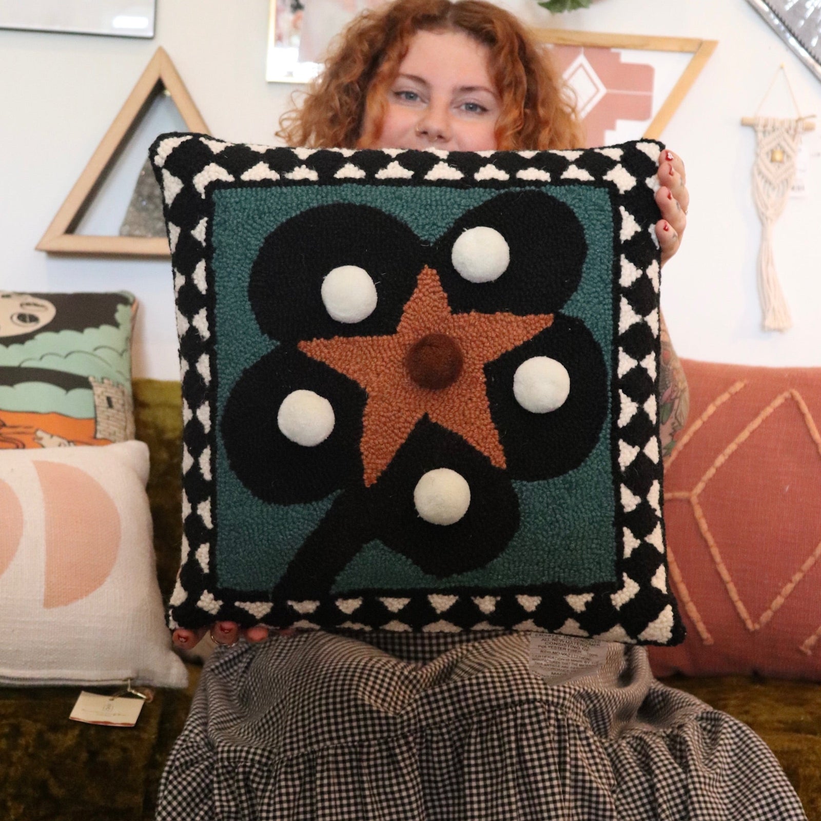 A woman holding theDiamonds & Pearls with Pom Poms Wool Hook Pillow.