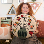 A woman holding the You Deserve Some Flowers Wool Hook Pillow with Pom Poms.