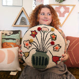 A woman holding the You Deserve Some Flowers Wool Hook Pillow with Pom Poms.
