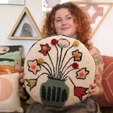 A woman holding the You Deserve Some Flowers Wool Hook Pillow with Pom Poms.