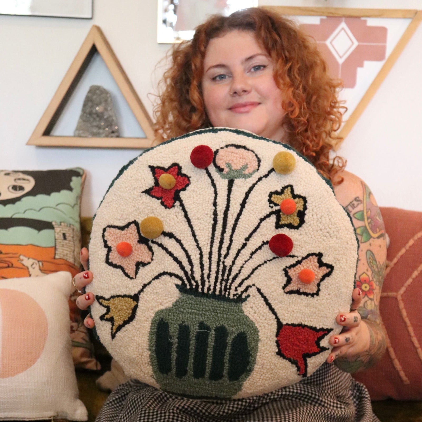 A woman holding the You Deserve Some Flowers Wool Hook Pillow with Pom Poms.