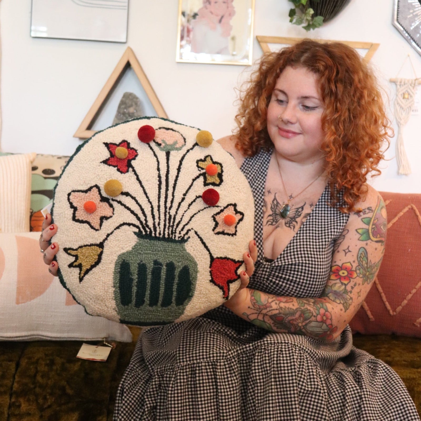A woman holding the You Deserve Some Flowers Wool Hook Pillow with Pom Poms.