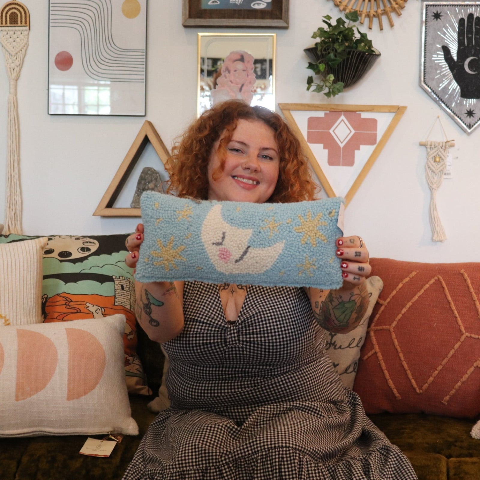 A woman holding the Moon And Stars Wool Hook Pillow.