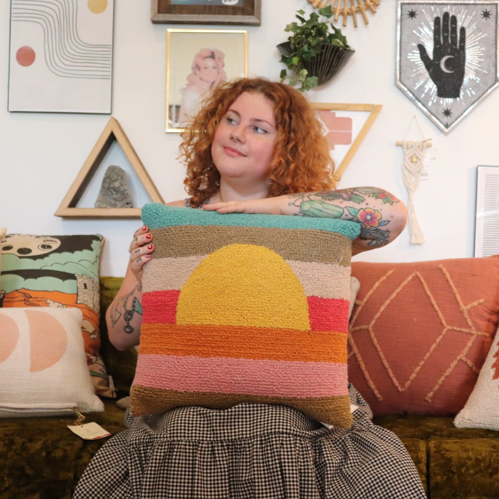 A woman holding the Sunset Waves Wool Hook Pillow.