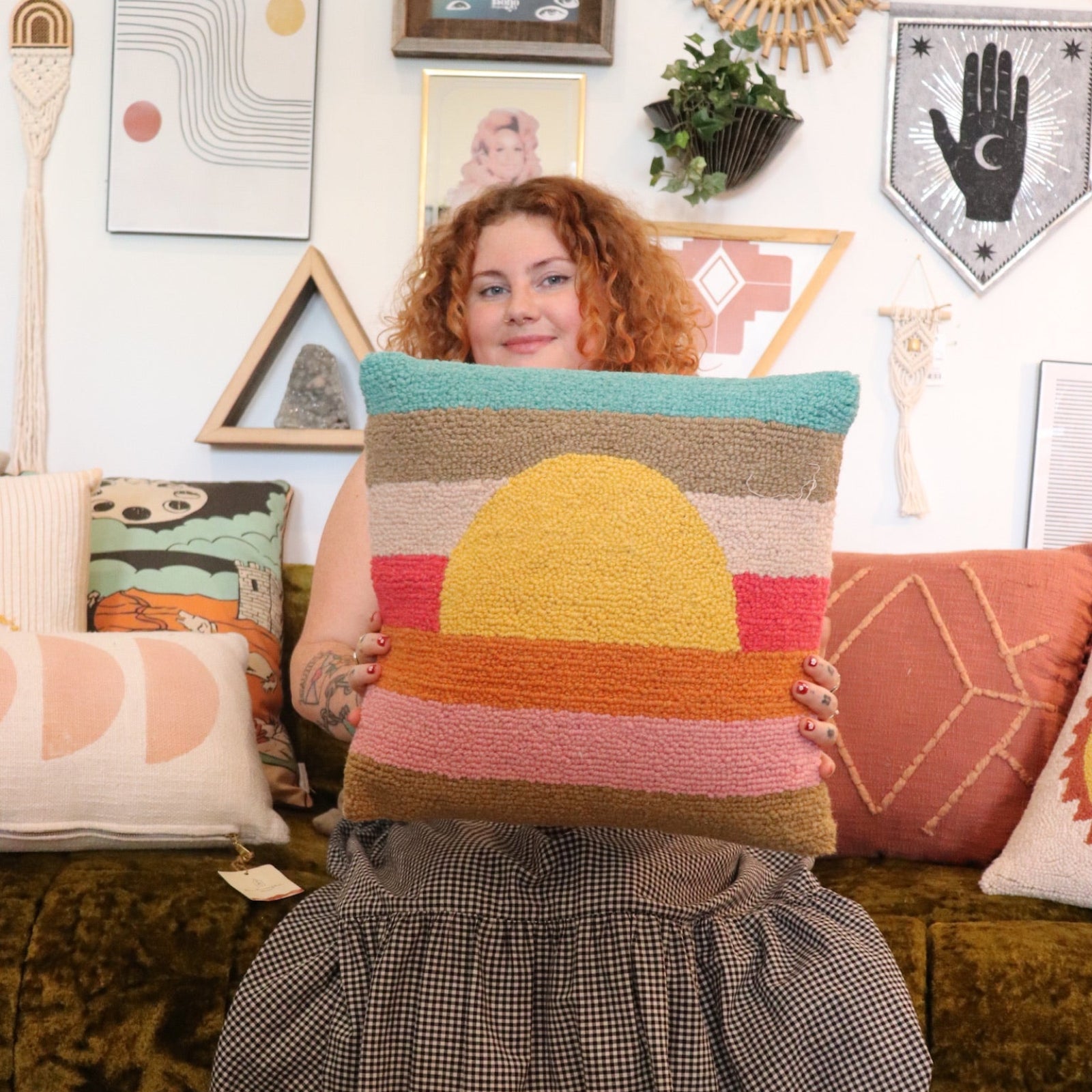 A woman holding the Sunset Waves Wool Hook Pillow.