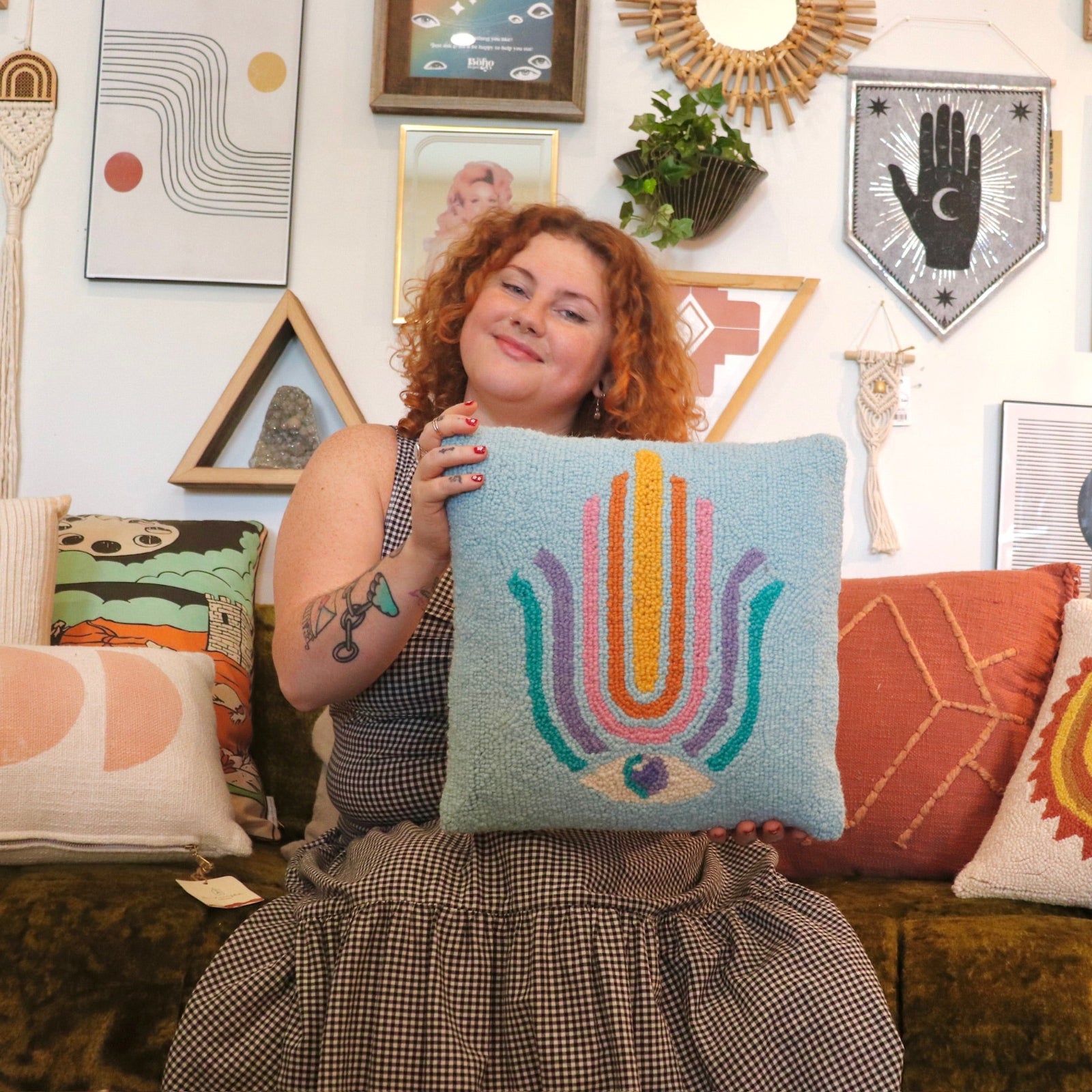 A woman holding the Ode To Intuition Wool Hook Pillow.
