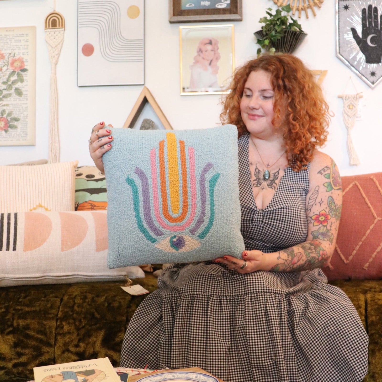 A woman holding the Ode To Intuition Wool Hook Pillow.