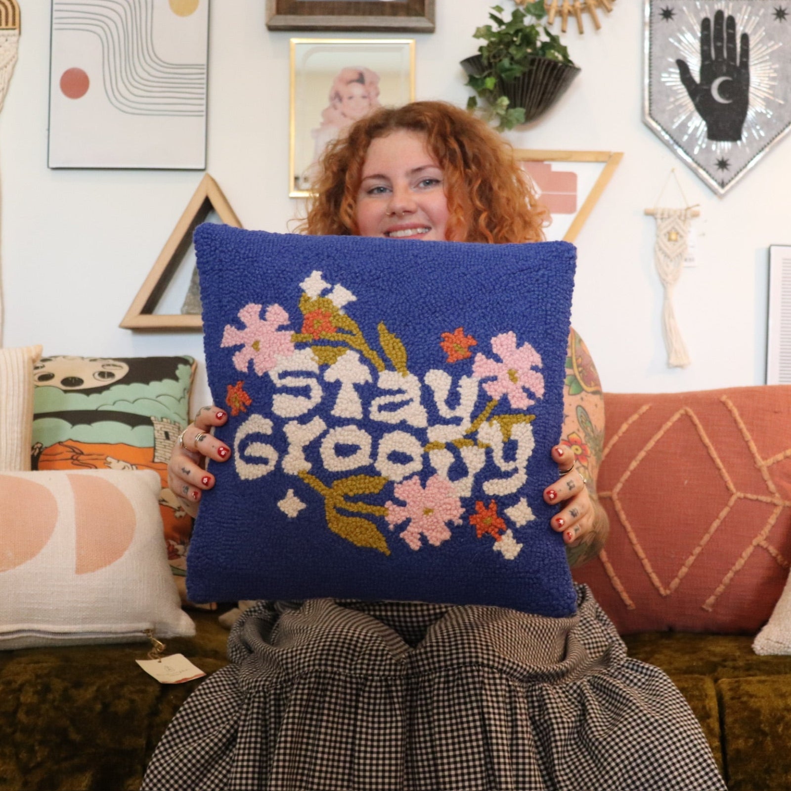 A woman holding the 'Stay Groovy' Wool Hook Pillow.