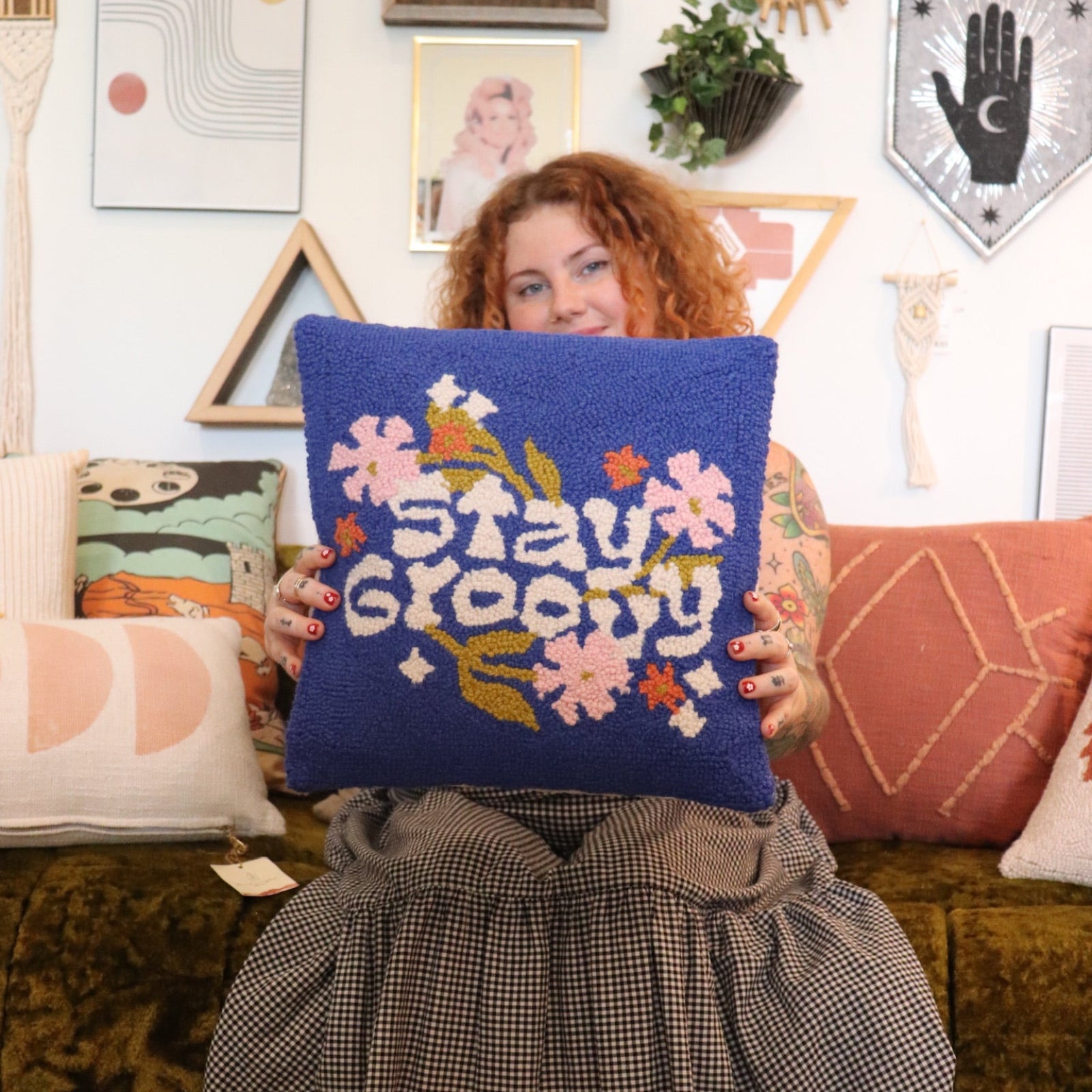 A woman holding the 'Stay Groovy' Wool Hook Pillow.