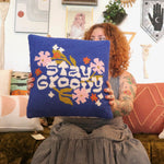 A woman holding the 'Stay Groovy' Wool Hook Pillow.