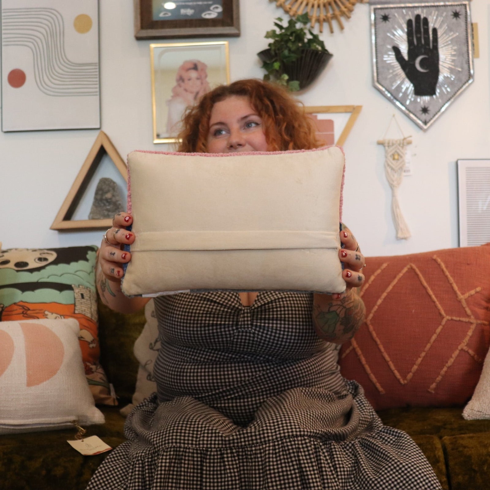 A woman holding the Sunset Wool Hook Pillow.
