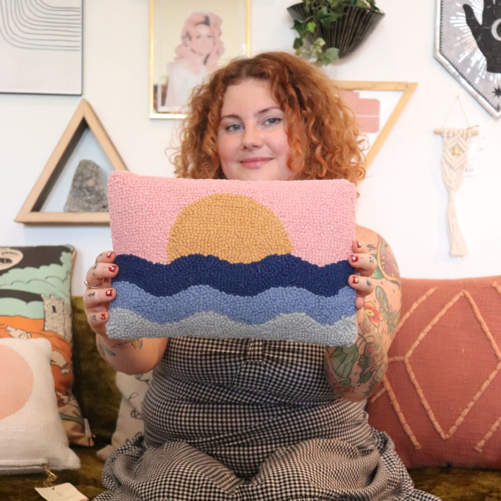 A woman holding the Sunset Wool Hook Pillow.